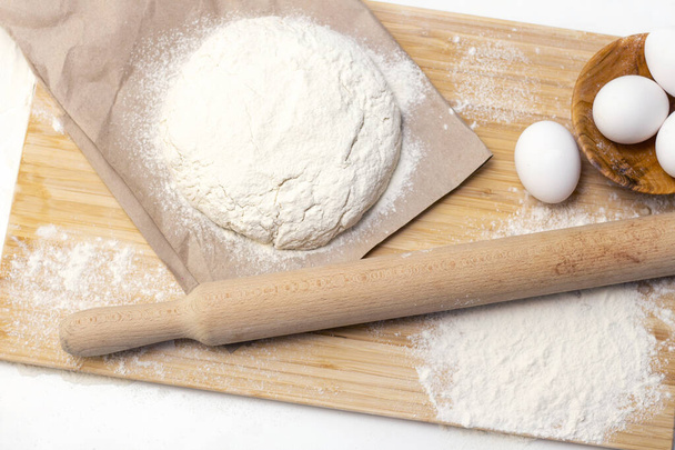 Home cooking concept. Female hands prepare homemade dough on a floured wooden board. - Fotoğraf, Görsel