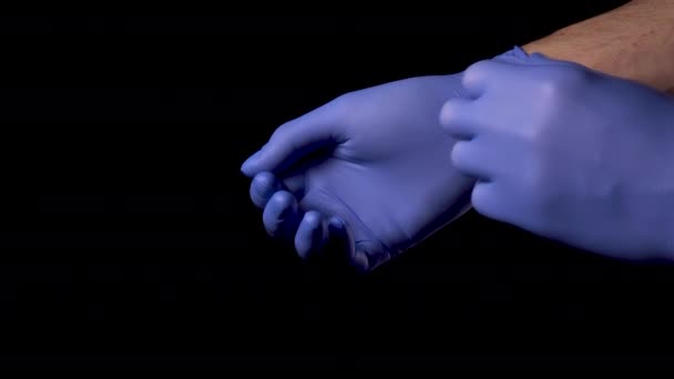 Doctor takes off protective medical gloves on a black background. Close up. Concept of means of protection against infection with coronavirus infection, COVID-19 - Filmagem, Vídeo
