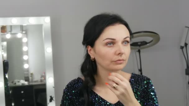 Mladá krásná showy žena před zrcadlem aplikuje make-up a nadace nebo maskér s rukama - Záběry, video