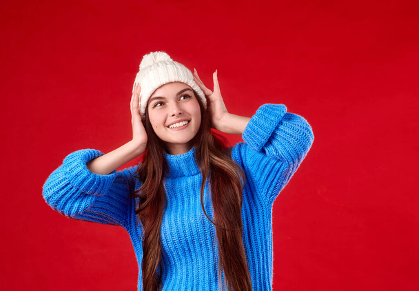  beautiful girl in a sweater and a hat on a red background - Valokuva, kuva