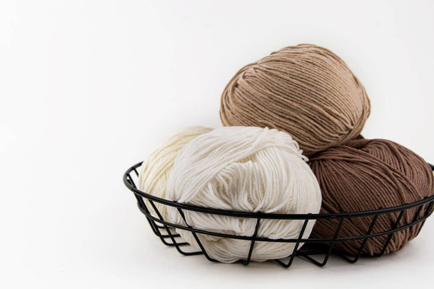 Balls of yarn for knitting brown flowers in a metal basket on a white background. - Fotó, kép