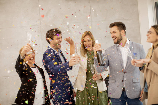 Grupo de empresarios entusiasmados celebrando y brindando con confeti cayendo en la oficina - Foto, Imagen