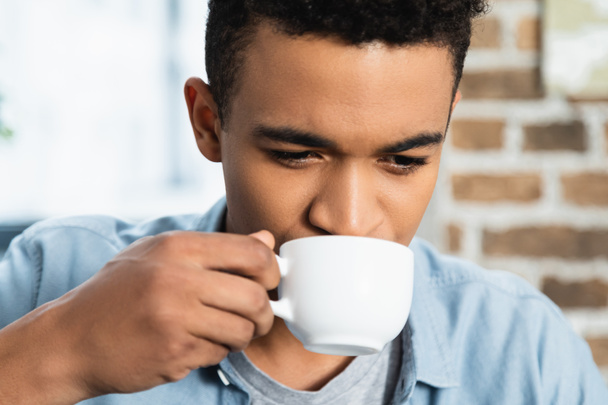 Afrikaans amerikaanse man die koffie drinkt in witte beker - Foto, afbeelding