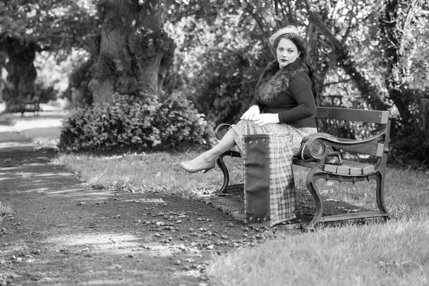 Mulher bonita posando em roupas vintage dos anos 1940, posando em um banco em um parque - Foto, Imagem