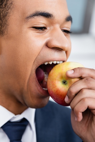 Afrikkalainen amerikkalainen liikemies puree omenaa  - Valokuva, kuva