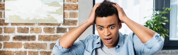 wstrząśnięty młody Afroamerykanin ciągnąc włosy, sztandar - Zdjęcie, obraz