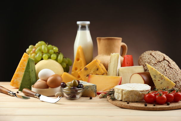 Tasty dairy products on wooden table, on dark background - 写真・画像