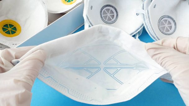 Hand in medical gloves packing many different respirators with high protection level. Protection against coronavirus. Respritors production, packing and delivery, closeu - Photo, Image