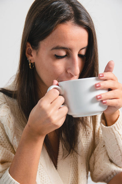 Evde rahat bir kadın sıcak yün elbiseli bir fincan kahve ya da çay içiyor. Evde olmak kavramı - Fotoğraf, Görsel