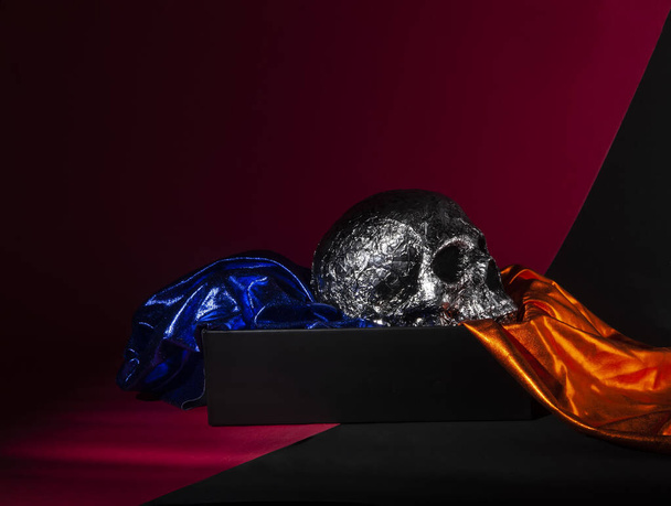 серебряный череп с оранжевой и синей тканью - Фото, изображение
