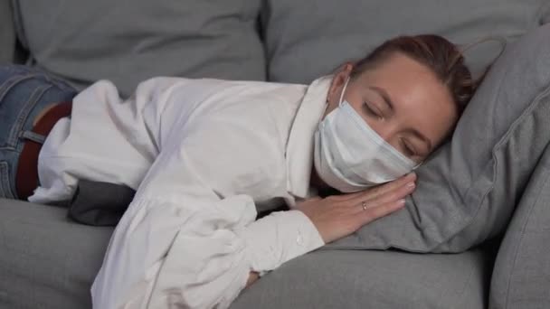 Um funcionário preguiçoso em uma máscara médica em seu rosto cai no sofá e adormece na hora do almoço - Filmagem, Vídeo