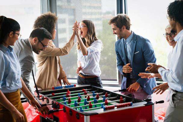 Business people having great time together. Colleagues playing table football in office - Φωτογραφία, εικόνα