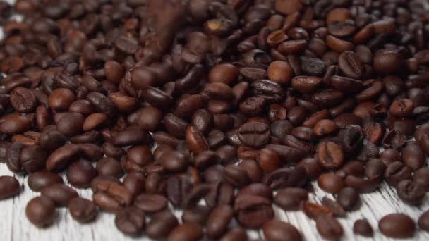 Gemischte geröstete Arabica und Robusta-Kaffeebohnen fallen langsam auf die Holzoberfläche. Zeitlupe. Nahaufnahme - Filmmaterial, Video