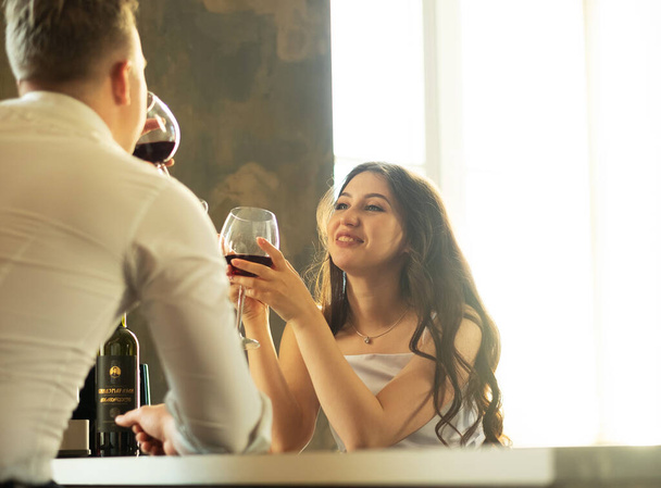 Young newlywed couple drinking wine and smiling at their happiness, romance and tenderness - Foto, imagen