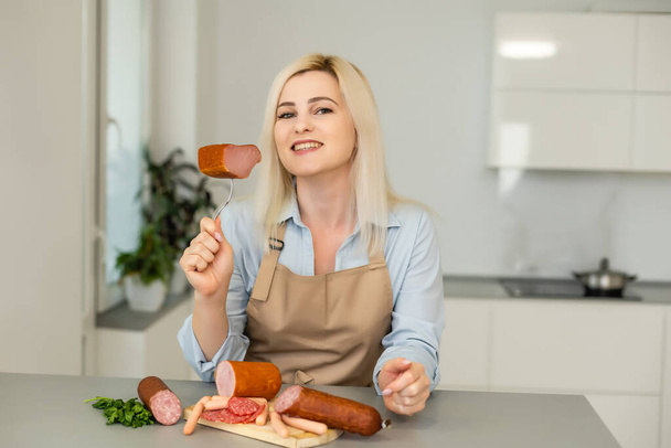 The girl is eating sausage. A piece of sausage. Smile and Joy. Business concept is the brand's appeal. Appetite - Photo, Image