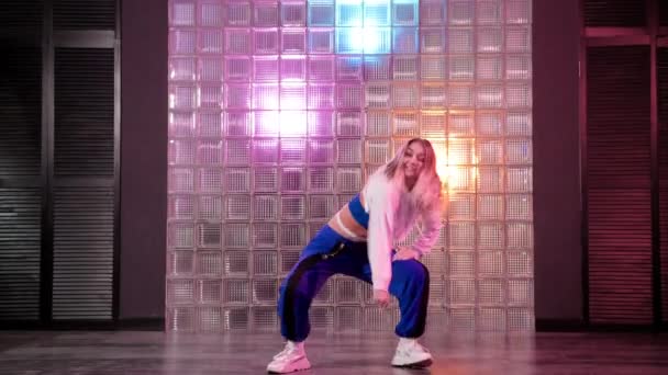 Wesoła młoda kobieta z długimi włosami tańczy hip hop w studio tańca. Skoki energicznie i patrząc w kamerę.  - Materiał filmowy, wideo