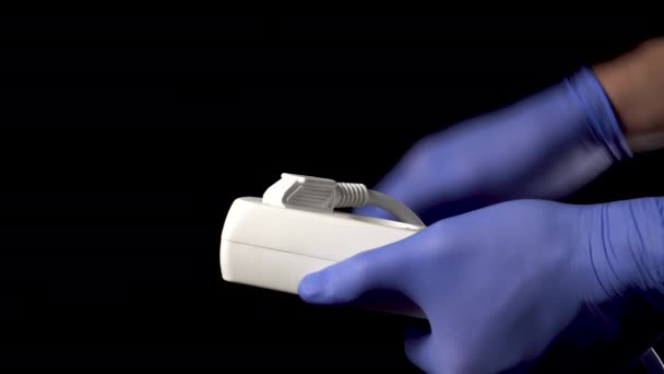 Mediziner mit Schutzhandschuhen ziehen den Stecker der medizinischen Geräte aus dem Stromnetz. Auf schwarzem Hintergrund Nahaufnahme - Filmmaterial, Video