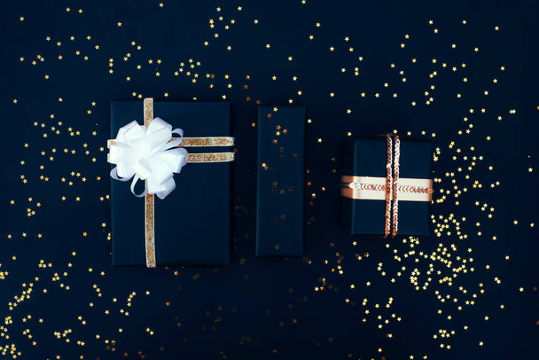 黒の背景にたくさんの包み隠された贈り物。新年の構図。クリスマスの構図. - 写真・画像