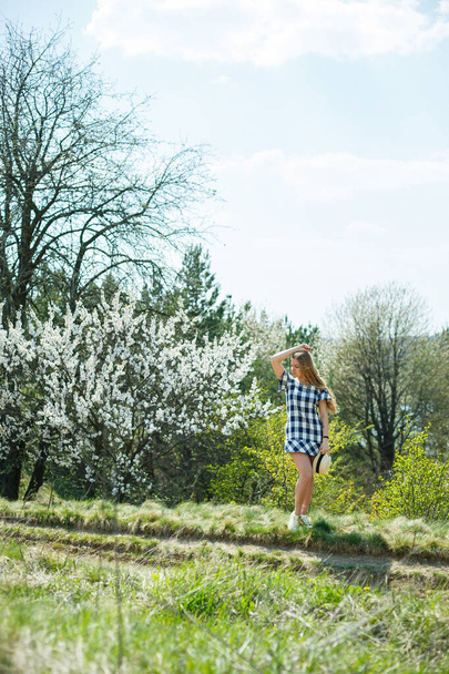 красивая девушка в платье ходить в весеннем лесу, где деревья цветут - Фото, изображение