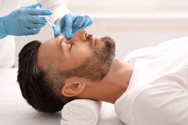 Вид на бородатого мужчину, получающего инъекцию красоты в салоне - Фото, изображение