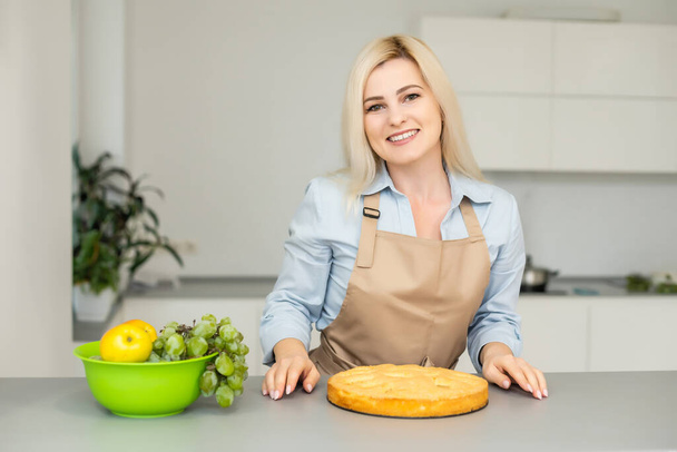 Beautiful woman holding pie in the kitchen - Zdjęcie, obraz