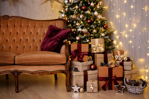 Christmas background - decorated Christmas tree, vintage sofa, festive garland lights and wrapped gift boxes - Photo, Image