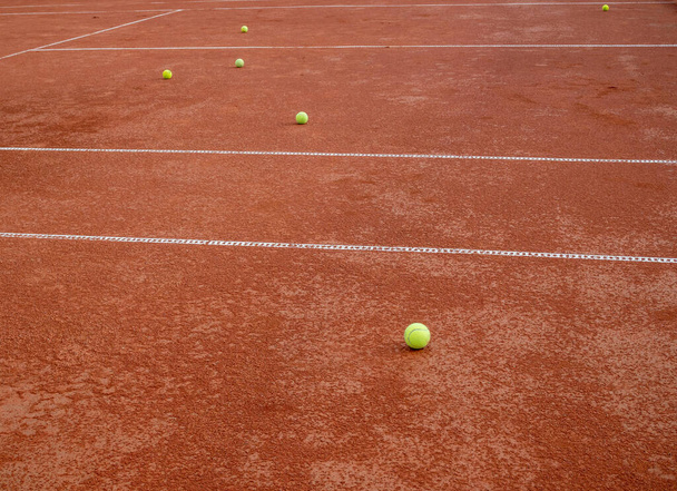 Dużo piłek tenisowych leżących na czerwonym korcie tenisowym. Koncepcja sportu i aktywności - Zdjęcie, obraz