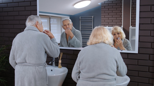 Seniorenpaar beim Zähneputzen und Blick in den Spiegel im heimischen Luxusbad - Foto, Bild