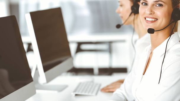 Blond female customer service representative and her colleague are consulting clients online using headset. Call center and business people concept - Foto, immagini