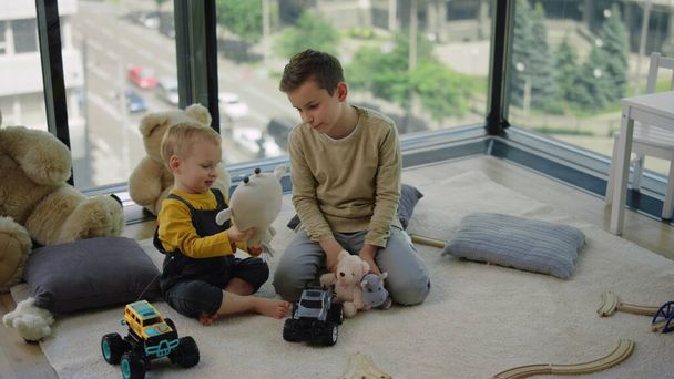 Dos hermanos jugando con juguetes blandos. Adorables niños sentados en la alfombra en casa. - Foto, imagen
