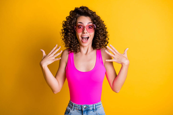 WOW. Photo of attractive girlish wavy lady open mouth overjoyed see shopping banner low prices not believe eyes wear pink sun glasses singlet isolated yellow shine color background - Фото, изображение