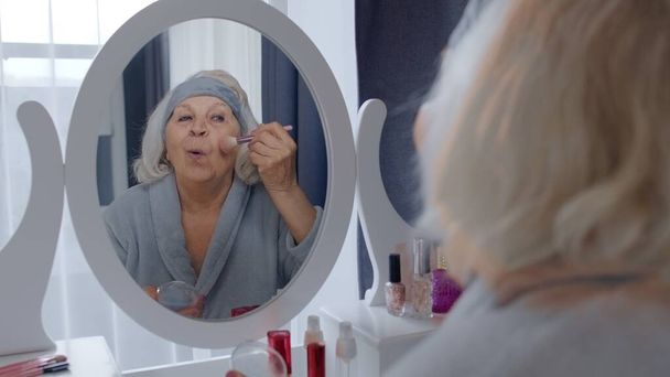 Velha avó de mulher sênior cuidando da pele, aplicando pó de fundação anti-rugas com escova - Foto, Imagem