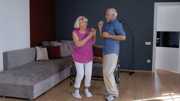 Senior couple dancing laughing at home. Grandparents relaxing having fun celebrating anniversary - Φωτογραφία, εικόνα