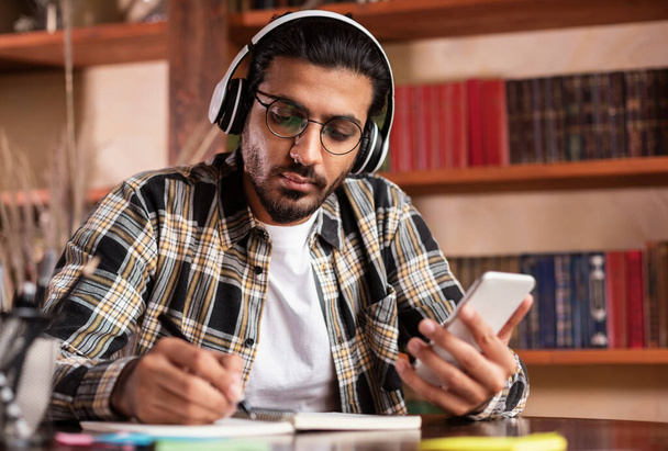 Indian Student Guy Using Smartphone Learning In University Library - Foto, imagen