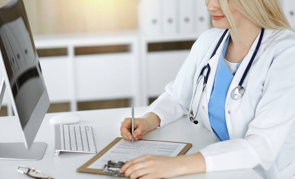 Mujer-médico desconocido en el trabajo llenar el formulario de registro de la historia de la medicación en la clínica soleada, primer plano - Foto, Imagen