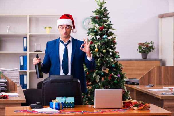 Νεαρός υπάλληλος γιορτάζει τα Χριστούγεννα στο χώρο εργασίας - Φωτογραφία, εικόνα