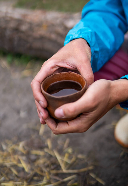 Beber té chino Pu Erh al aire libre Cerca del horno de fogata en Ecovillage. Tetera de arcilla, taza y olla en la mesita de madera - Foto, Imagen