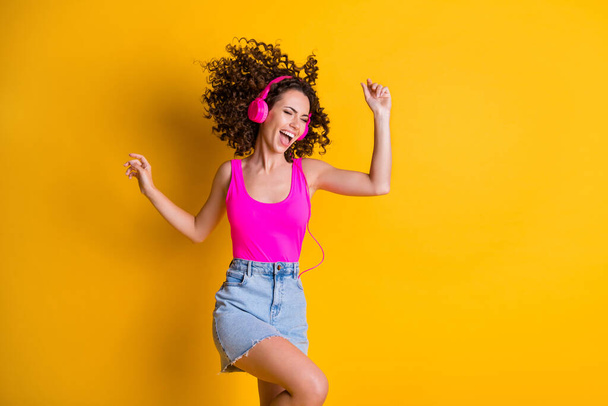 Photo of crazy pretty excited lady youth party wavy hairdo fly blow slim figure shape listen modern technology earflaps wear pink tank top denim mini skirt isolated yellow color background - Fotoğraf, Görsel