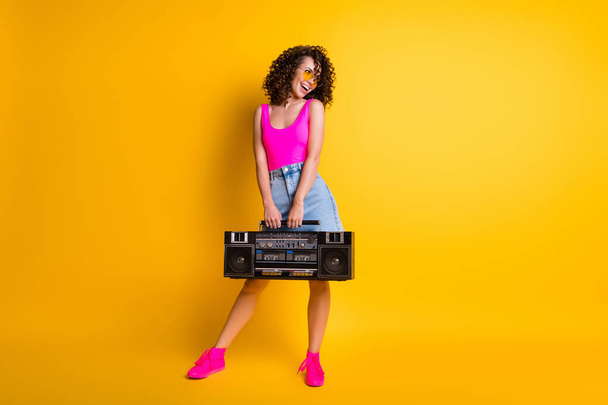 Full body photo of funny wavy hipster dj lady hold retro tape boom box ready event holiday beach pool party wear sun specs pink singlet denim skirt shoes isolated yellow color background - Foto, immagini