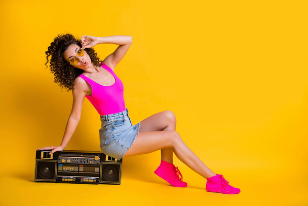 Full body profile photo of funny charming lady sit cozy boom box holiday party summer entertainment wear sun specs pink singlet denim skirt shoes isolated shine yellow color background - Foto, immagini