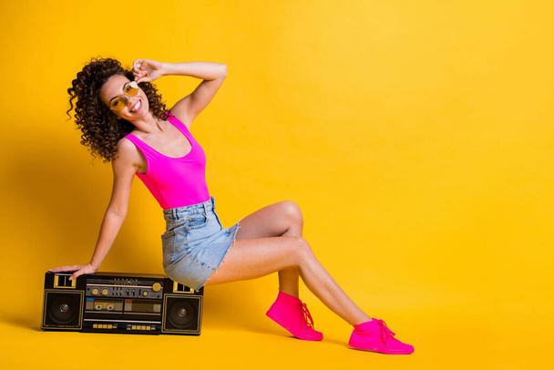 Full body profile photo of charming lady sit retro boom box holiday party entertain posing photographing wear sun specs pink singlet denim skirt shoes isolated shine yellow color background - Foto, immagini