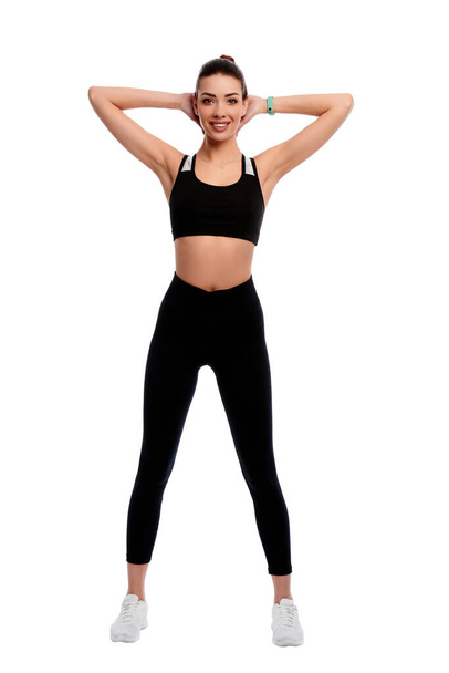 Fit strong sportswoman stretching hands on white isolated background. Fitness female doing physical exercise and smile. Healthcare and weight loss concept - Фото, изображение