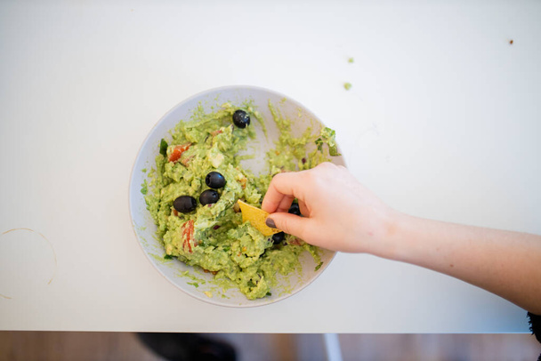 Nachos à tremper à la main dans une sauce guacamole aux olives - Photo, image