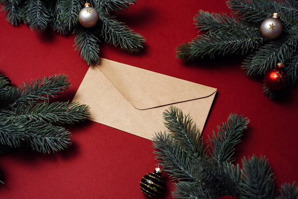 Закрытый конверт рядом с рождественскими ветками и украшениями, шарами. Новогодний праздник - Фото, изображение