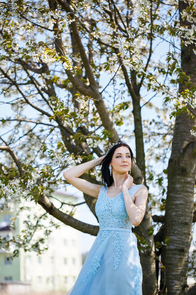 Kaunis tyttö vaalean kesän sininen pitkä mekko koristeltu hänen hiukset vastaan kukkiva puu. Tarjous muotokuva nuori nainen valkoinen kukka - Valokuva, kuva