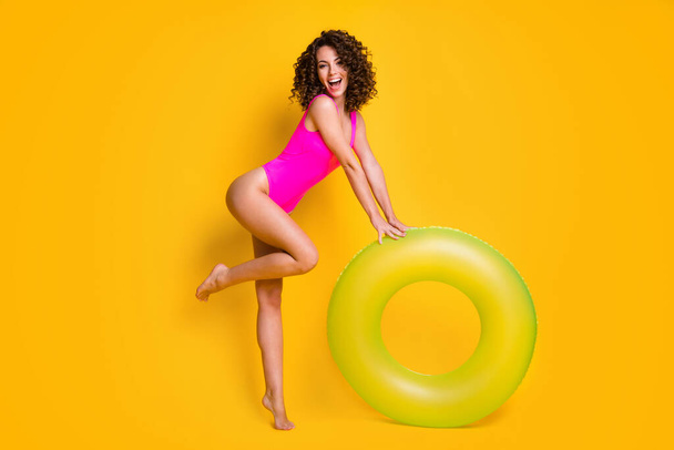 Full length profile photo of attractive excited flirty funny playful lady relax rest resort prepare swim big round circle water wear pink swimsuit isolated vivid yellow color background - Foto, immagini