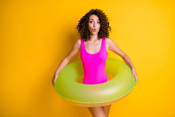 Photo of attractive funny terrified lady relax rest resort prepare swim big round circle afraid step into water frightened face wear pink swimsuit isolated vivid yellow color background - Foto, imagen