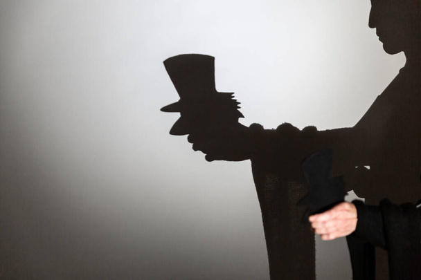 juego sombra proyectada en una pantalla blanca. las manos de la persona dan forma a un caballero que lleva un sombrero, bufanda y fumar una pipa. - Foto, Imagen
