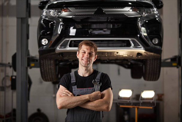 portrait of confident mechanic in uniform posing at camera in auto service - Фото, зображення