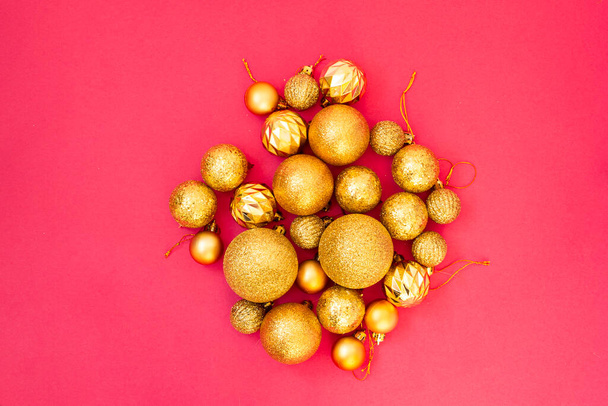 Gold glitter. Christmas balls of different sizes are collected in a bunch on a pink background. Flat lay, top view - Foto, Imagem